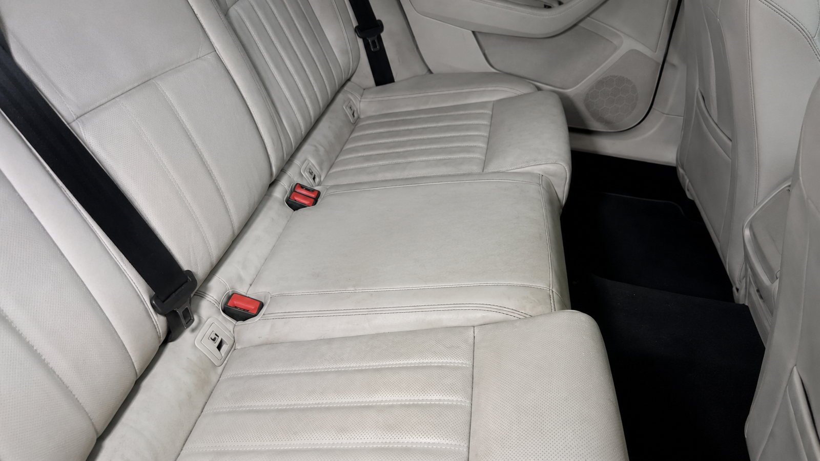 Banquette arrière en cuir beige d'une berline, grisée et marquée par l'usage, avant nettoyage