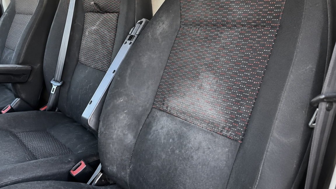 Siège conducteur en tissu noir taché et auréolé, avant shampoing par injection-extraction