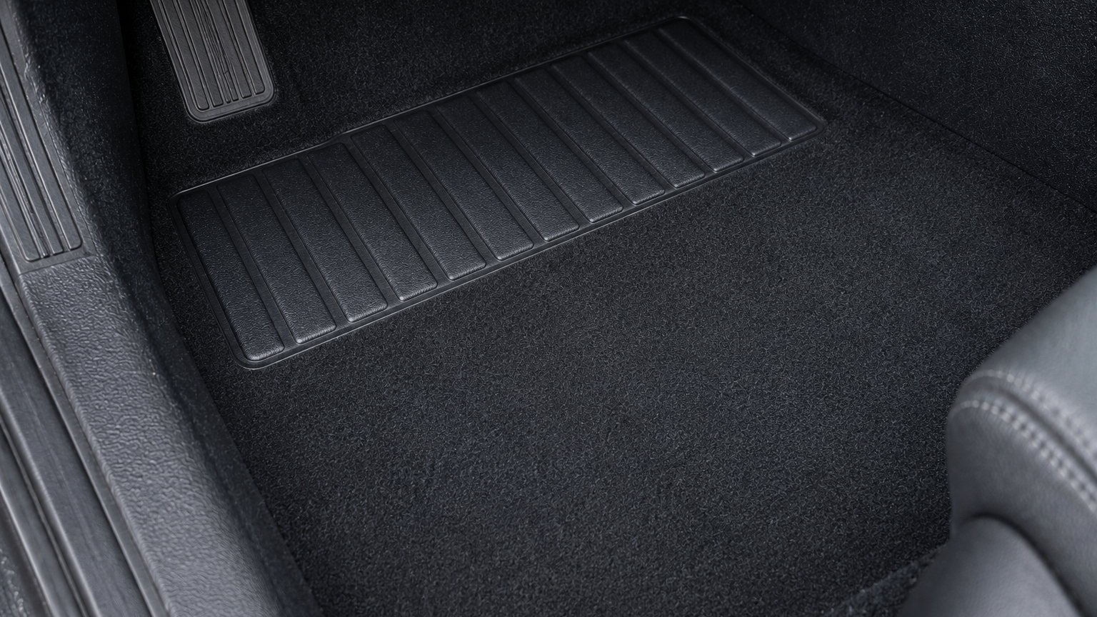 La même moquette de plancher, uniformément noire et sans débris, après nettoyage à l'atelier AutoClean Diois